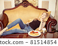 Beautiful young adult blond woman watching TV set 81514854