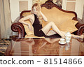 Beautiful young adult blond woman sitting on sofa 81514866
