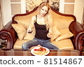 Beautiful young adult blond woman watching TV set 81514867