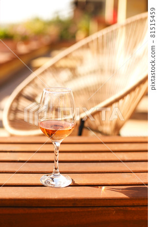 Glass of white wine on rustic wooden table and flower pots on terrace outside Glass of white wine on rustic wooden table and flower pots on terrace outside 81515459