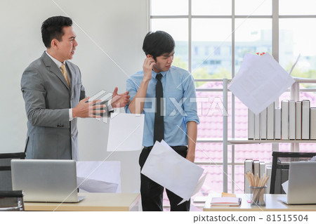 Asian businessman manager in suit throwing paperwork into air and blaming for young employee with anger and serious gesture. Office work problem and job quality conflict concept. 81515504