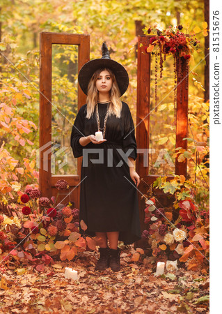 Witch costume and hat looking mysteriously at candle in her hands Witch costume and hat looking mysteriously at candle in her hands 81515676