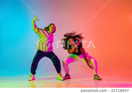 Two beautiful stylish hip-hop dancers on colorful gradient background in neon lights Two beautiful stylish hip-hop dancers on colorful gradient background in neon lights 81516647