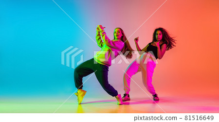 Two beautiful talented hip-hop dancers on colorful gradient background in neon lights 81516649