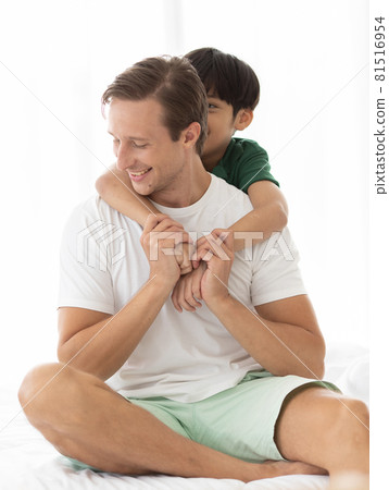 Caucasian dad and mixed-race son cuddle and playing together in fun and intimate manner 81516954