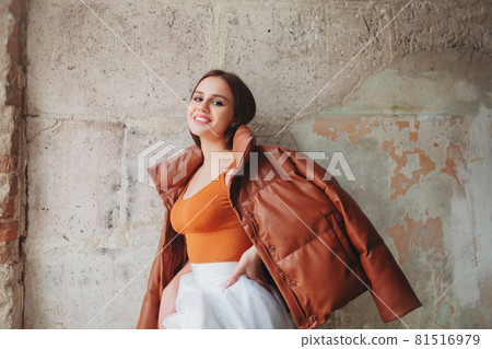 Cheerful stylish woman near weathered wall Cheerful stylish woman near weathered wall 81516979