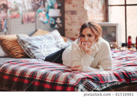 Young woman resting on bed against retro posters Young woman resting on bed against retro posters 81516981