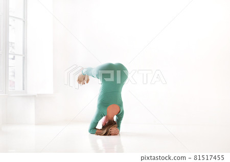 Slim woman doing balancing handstand asana Slim woman doing balancing handstand asana 81517455