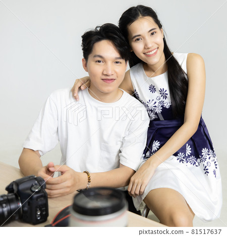 Asain man photographer and girlfriend Sitting on a man photography in lap. Atmosphere in the room is cozy at studio. Concept cozy photographer in studio. 81517637