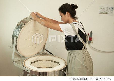 Artisan with electric oven in pottery workshop 81518479
