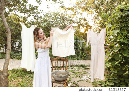 Young woman hanging laundry outdoors 81518857