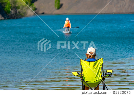 rear view, a little girl, a teenager, a child, sitting on a camping tourist chair 81520075