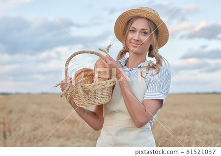Female farmer standing wheat agricultural field Woman baker holding wicker basket bread product 81521037