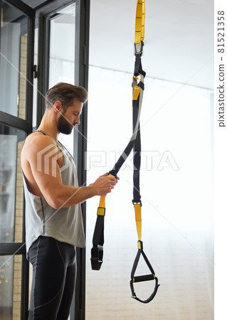 Athletic young man preparing resistance band for home workout Athletic young man preparing resistance band for home workout 81521358