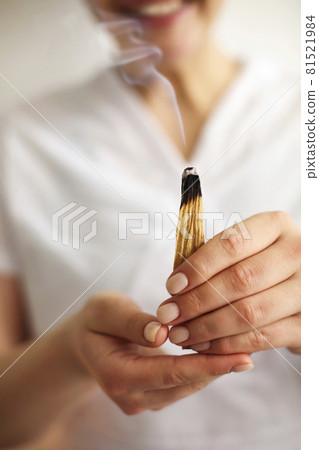 Cropped shot of smiling SPA worker in white uniform holding burning palo santo incense Cropped shot of smiling SPA worker in white uniform holding burning palo santo incense 81521984