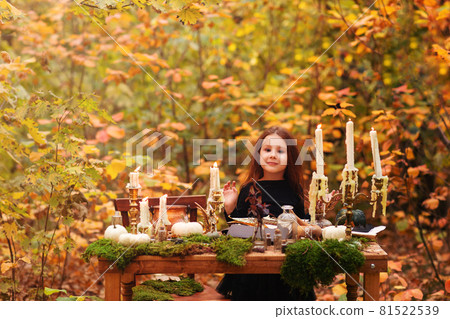 Little adorable girl in black witch costume playing in autumn forest during Halloween Little adorable girl in black witch costume playing in autumn forest during Halloween 81522539