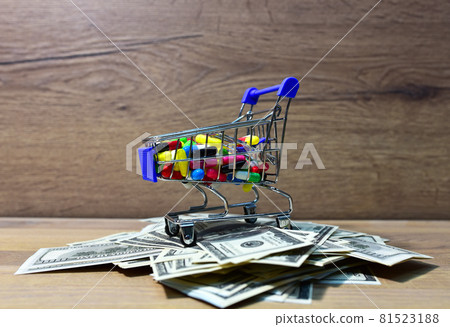 Pills in a shopping basket on a heap of American dollars. Pills in a shopping basket on a heap of American dollars. 81523188