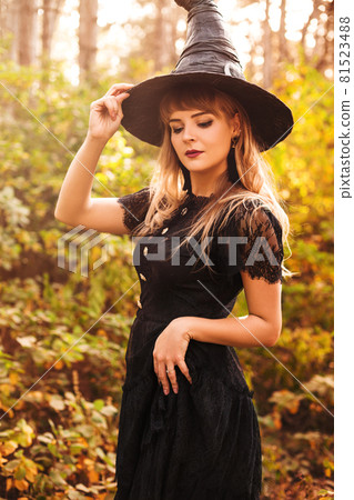 Young witch with jack o lantern in forest Young witch with jack o lantern in forest 81523488