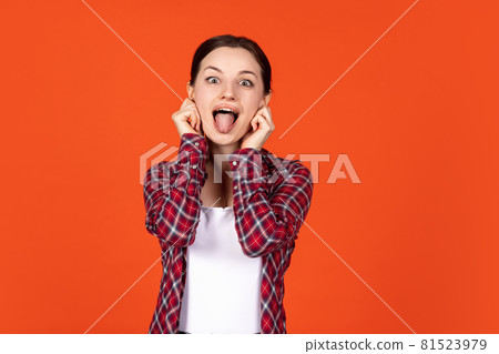Funny portrait of young beautiful smiling girl isolated on orange studio background 81523979