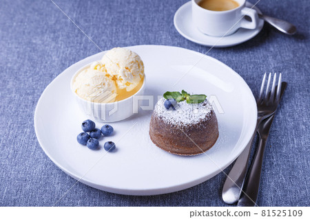 Lava cake - chocolate fondant cake with vanilla ice cream, blueberries, mint and coffee. Traditional French pastries. Close-up. Lava cake - chocolate fondant cake with vanilla ice cream, blueberries, mint and coffee. Traditional French pastries. Close-up. 81525109