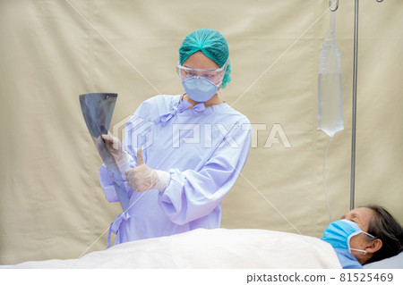 The doctor is explaining the results of the lung x-ray to an elderly patient who is lying on the bed in the hospital room The doctor is explaining the results of the lung x-ray to an elderly patient who is lying on the bed in the hospital room 81525469