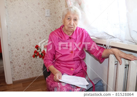 Woman holding cash in front of heating radiator. Payment for heating in winter. Selective focus. 81528864