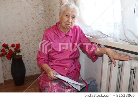 Woman holding cash in front of heating radiator. Payment for heating in winter. Selective focus. 81528866