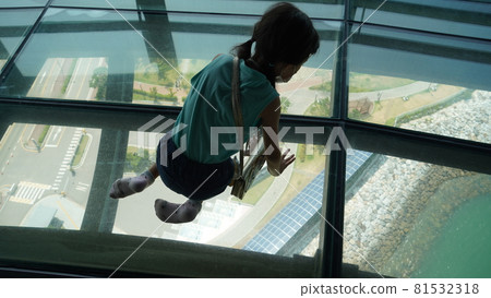 A girl looking down the glass floor of an observation deck A girl looking down the glass floor of an observation deck 81532318