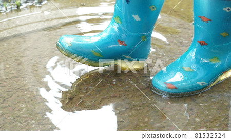 A child's feet in boots on a puddle on a rainy day 81532524