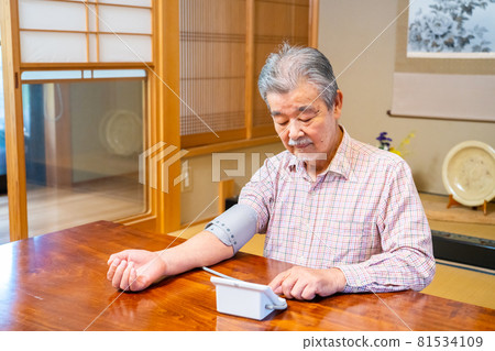 Senior man measuring blood pressure in a Japanese-style room 81534109