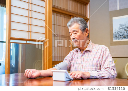 Senior man measuring blood pressure in a Japanese-style room 81534110