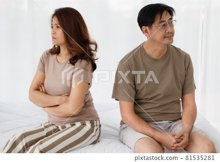 Portrait of middle-aged Asian lover couple sitting on a bed at home and arguing about the family financial problem. Woman crossed arm to show her disappointment. Concept of problems in a relationship Portrait of middle-aged Asian lover couple sitting on a bed at home and arguing about the family financial problem. Woman crossed arm to show her disappointment. Concept of problems in a relationship 81535281
