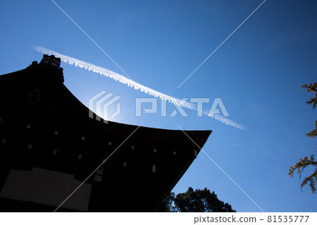 Shrine roof silhouette and vapor trail blue sky background 81535777