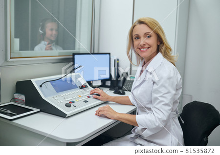 Joyous middle-aged doctor performing an audiometry test Joyous middle-aged doctor performing an audiometry test 81535872
