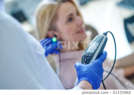 Experienced audiologist measuring the patients auditory acuity with an audiometer Experienced audiologist measuring the patients auditory acuity with an audiometer 81535968