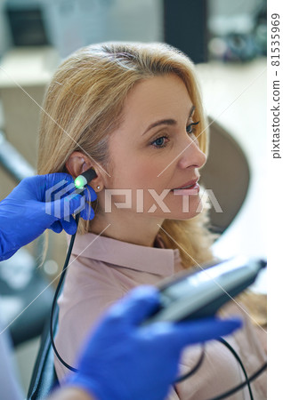 Calm attractive blonde middle-aged woman having her hearing checked Calm attractive blonde middle-aged woman having her hearing checked 81535969