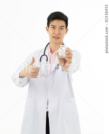 Portrait of Asian male doctor in white gown coat holding a bottle of coronavirus covid-19 vaccine in hand and thumb up, pose on white background. Portrait of Asian male doctor in white gown coat holding a bottle of coronavirus covid-19 vaccine in hand and thumb up, pose on white background. 81536455