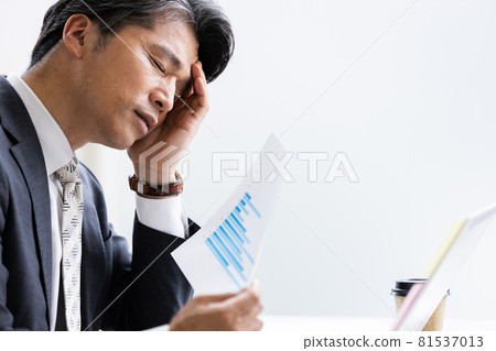 A businessman holding his head during desk work 81537013