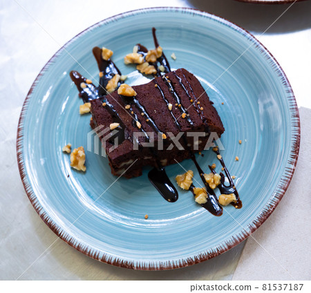 Piece of chocolate cake with chocolate mousse and nuts for decoration 81537187