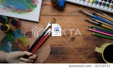Above view paint brushes, watercolors and palette on wooden table. Above view paint brushes, watercolors and palette on wooden table. 81538752