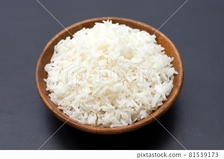 Dish of rice in wooden bowl on dark background. Dish of rice in wooden bowl on dark background. 81539173