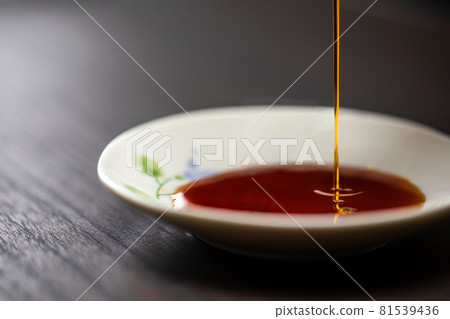 Close-up of soy sauce poured into a small plate on a wood-grained table Close-up of soy sauce poured into a small plate on a wood-grained table 81539436