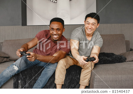 Two friends playing Playstation in the living room Two friends playing Playstation in the living room 81540437