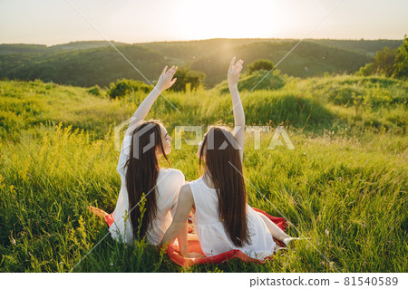 Portrait of two sisters in white dresses with long hair in a field 81540589
