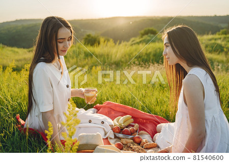 Portrait of two sisters in white dresses with long hair in a field 81540600