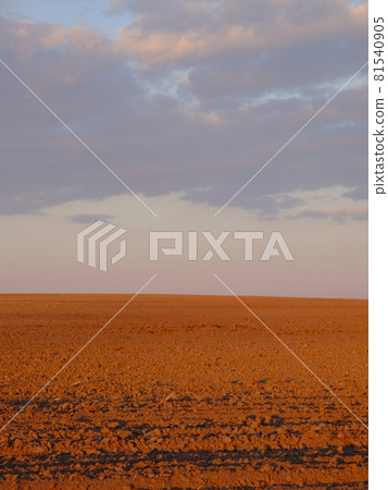 Cloudy evening sky over an empty agricultural field. Bright sunset landscape. 81540905