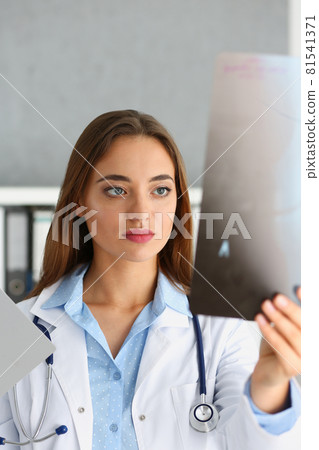 Female beautiful doctor hold in hand and look at xray Female beautiful doctor hold in hand and look at xray 81541371