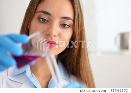 Female chemist holds test tube of glass in his hand overflows a liquid 81541372