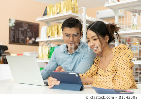 Two happy cafe managers working and meeting on laptop in their coffee shop. 81542592