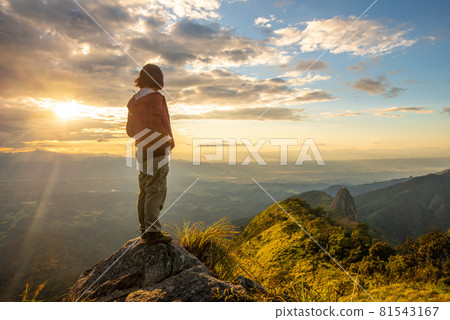 Back view of tourist woman standing on the rock and looking to beautiful view of Doi Nork in Doi Luang national park in Phayao province of Thailand at sunset. Back view of tourist woman standing on the rock and looking to beautiful view of Doi Nork in Doi Luang national park in Phayao province of Thailand at sunset. 81543167